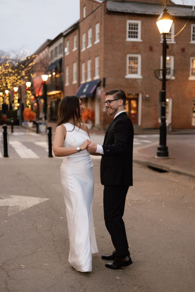 Wide shot of couple dancing on the brick sidewalk 
of King Street in Old Town Alexandria during their 
casual elopement — Kelly Wineinger Creative