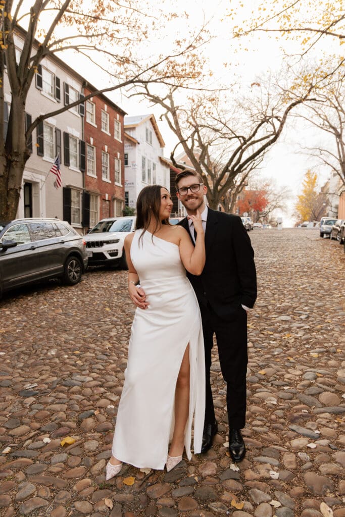 Wide shot of bride and groom on the historic cobblestone streets of Old Town Alexandria surrounded by colonial architecture during their 
intimate elopement — Kelly Wineinger Creative