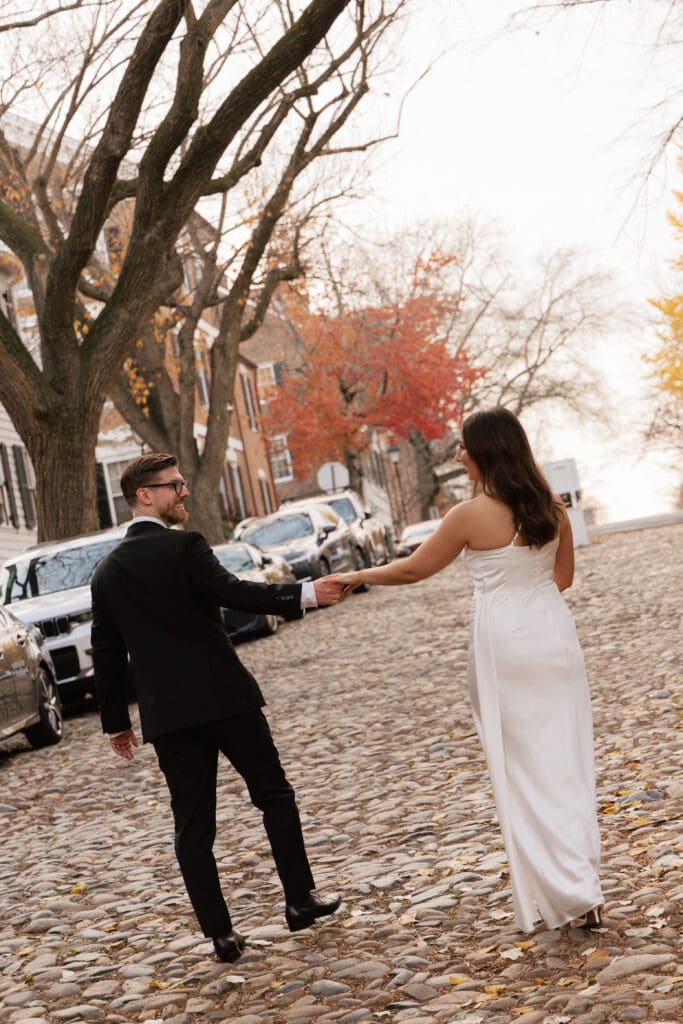Newlywed couple walking hand in hand down the historic cobblestone streets of Captain's Row in 
Old Town Alexandria on their elopement day — Northern Virginia elopement photographer  Kelly Wineinger Creative