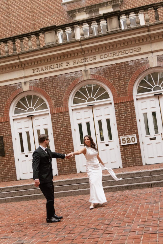 Groom dancing with bride during a cinematic moment in front of the Alexandria Courthouse 
during their Old Town Alexandria elopement — 
Kelly Wineinger Creative