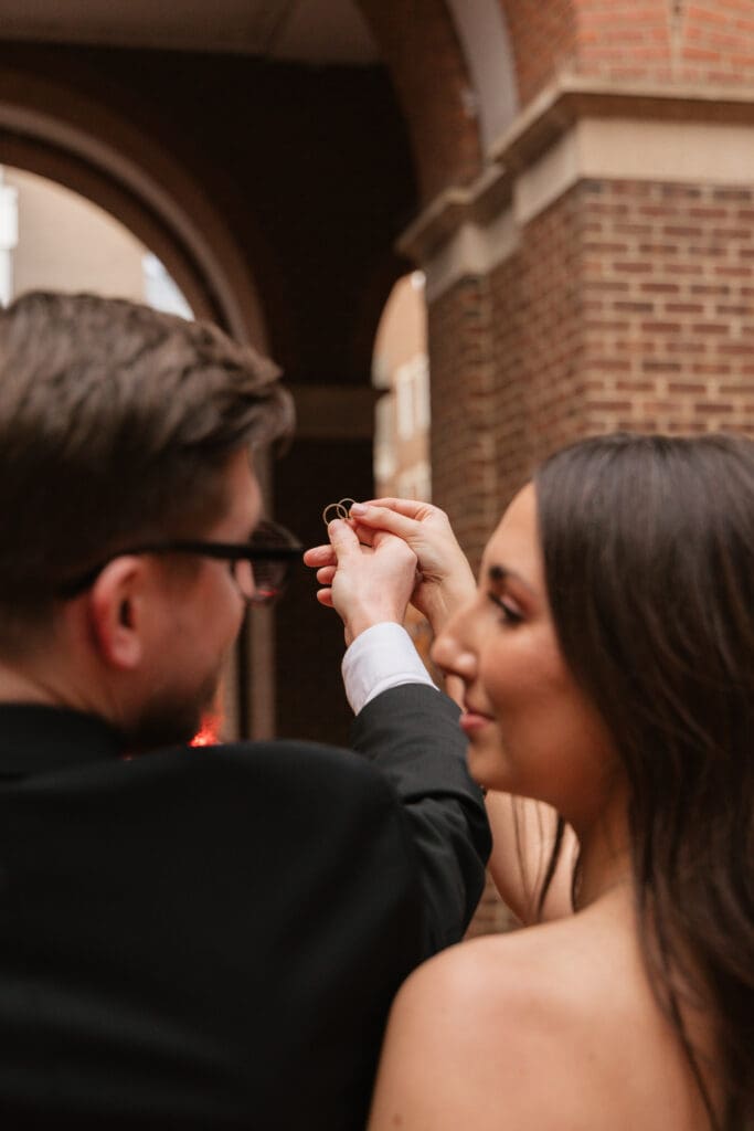 Bride and groom detail portrait against the 
classic brick and white column architecture of 
the Alexandria Virginia Courthouse — Old Town 
elopement photography by Kelly Wineinger Creative