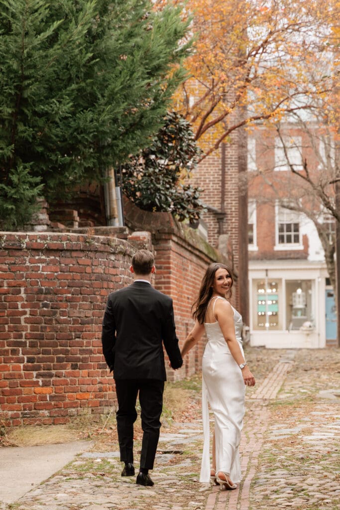 Bride and groom walking together down Wales Alley, one of Old Town Alexandria's oldest cobblestone 
streets, during their casual fall elopement — Northern Virginia elopement photographer