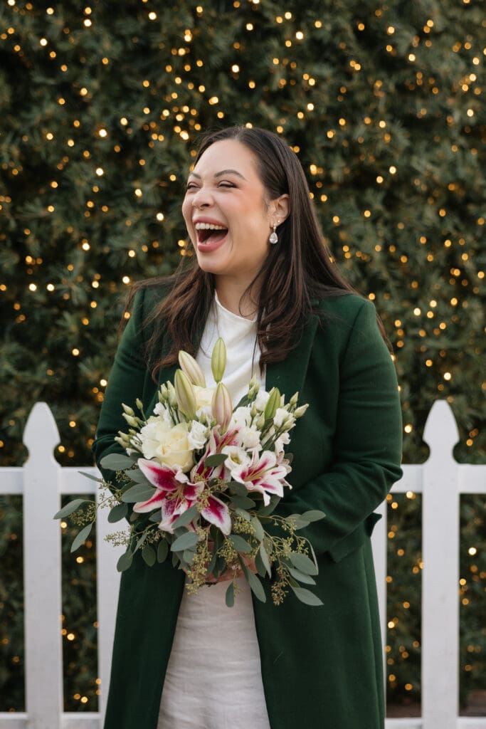 Bride laughs while holding pink and white floral bouquet after an intimate Northern VA wedding ceremony