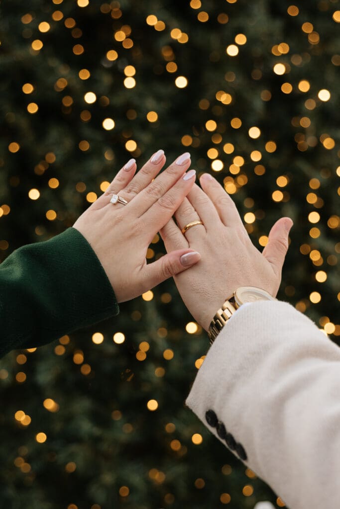Bride and groom admire their new wedding bands in front of a Christmas tree after their elopement ceremony