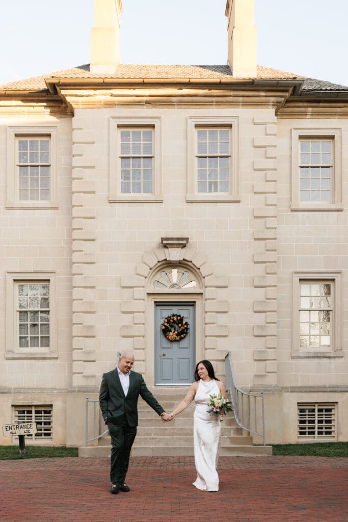 newlywed couple walks in from of Carlyle house for bridal portraits in Northern Virginia