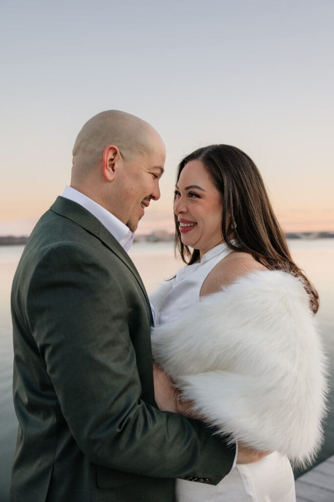 bride and groom smile at each other during waterfront bridal portraits in Old Town Alexandria