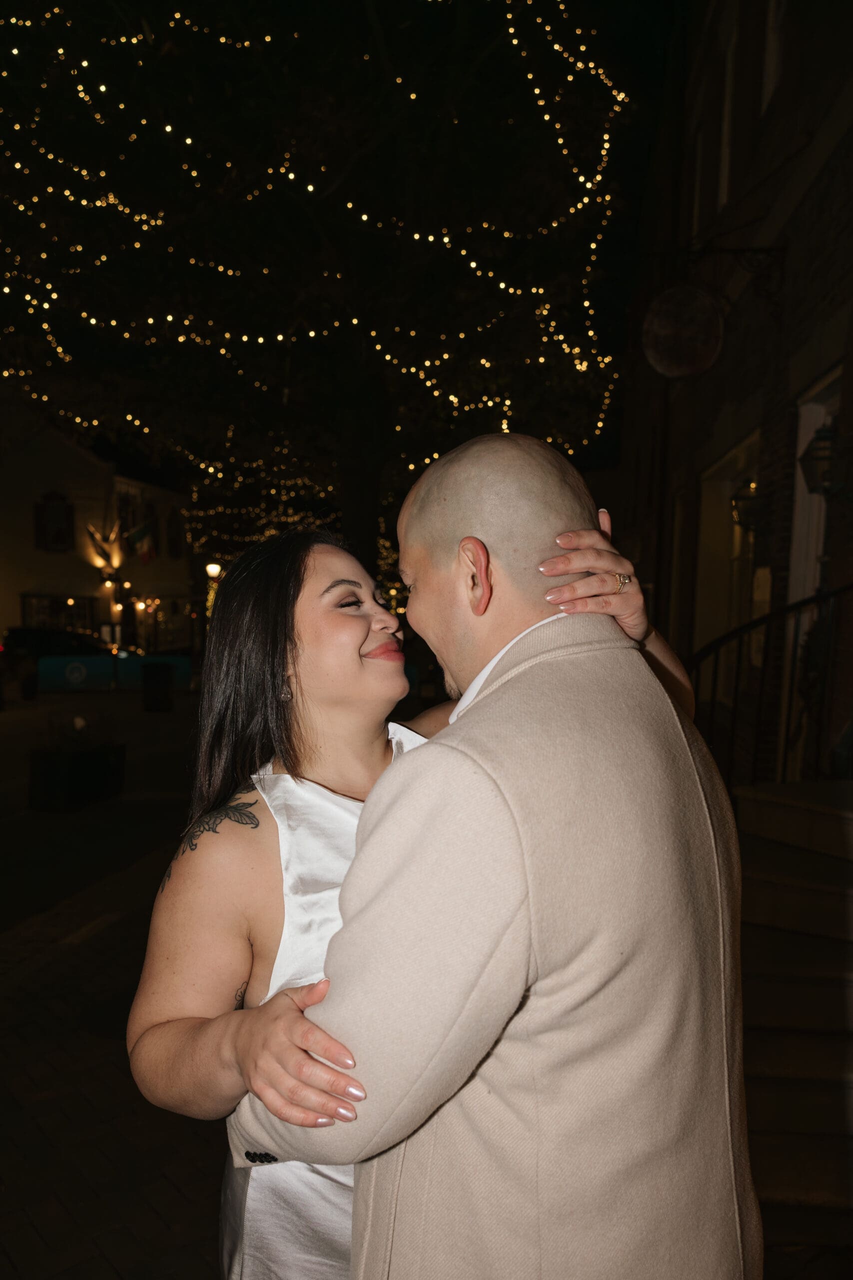 couple gazes at each other lovingly beneath the twinkle lights in Old Town Alexandria after their wedding day