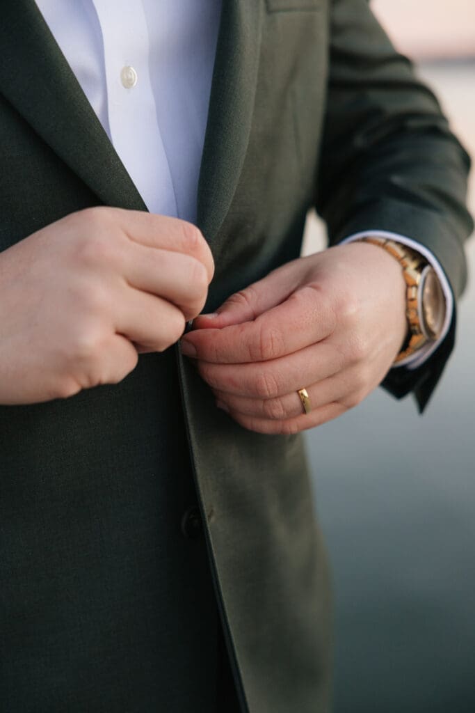 groom buttons his suit jacket during waterfront elopement photos in Old Town Alexandria
