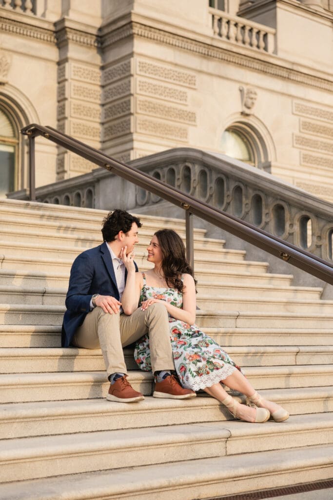 couple sits on the steps of the Library of Congress in Washington DC during an engagement photoshoot