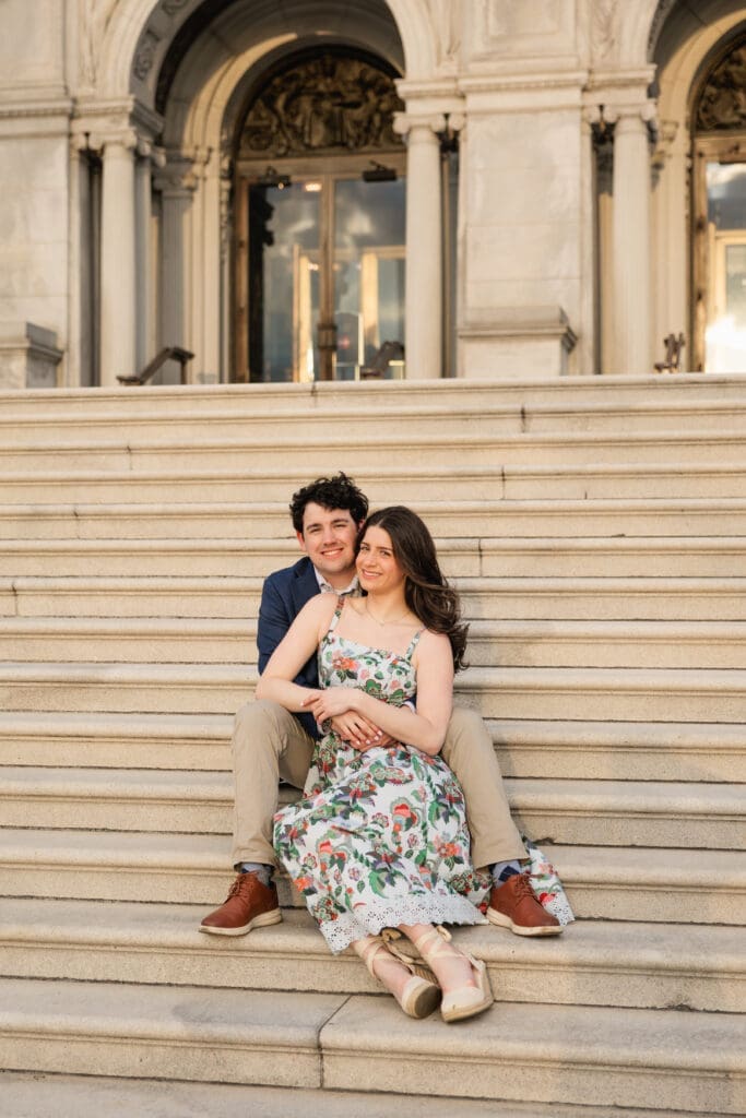 Couple sits on the steps of the Library of Congress during a spring engagement photoshoot