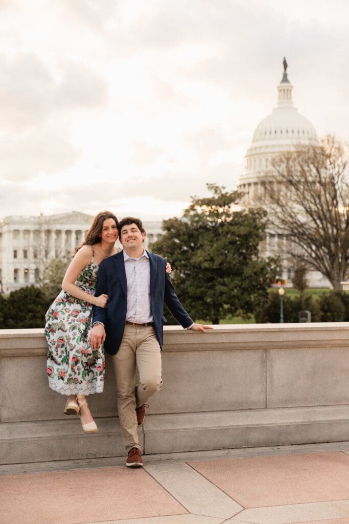 couple poses together for engagement photos with views of the US Capitol building in the background in Washington DC