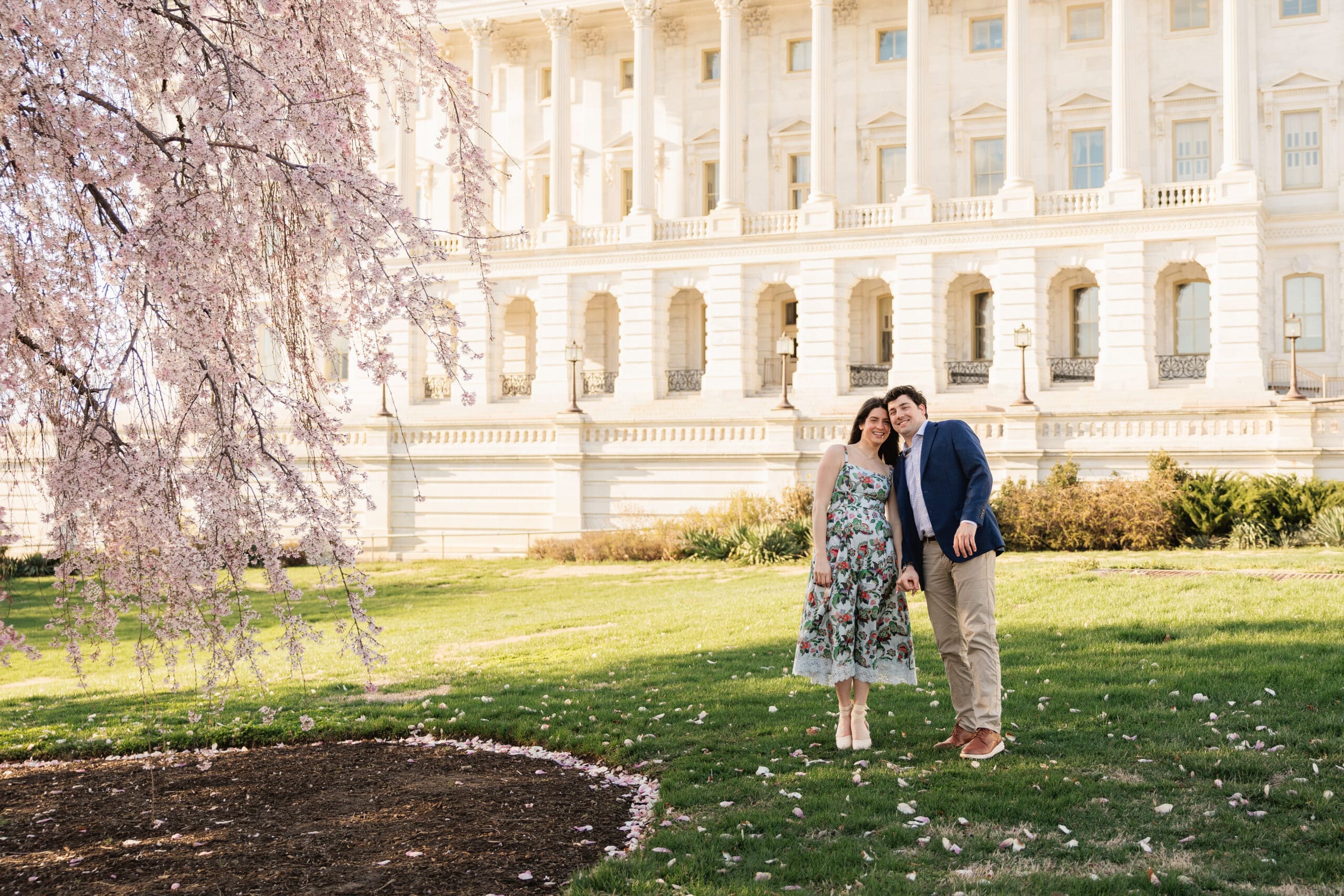 Couple smiles for an engagement photo surrounded by spring blooms in Washington DC