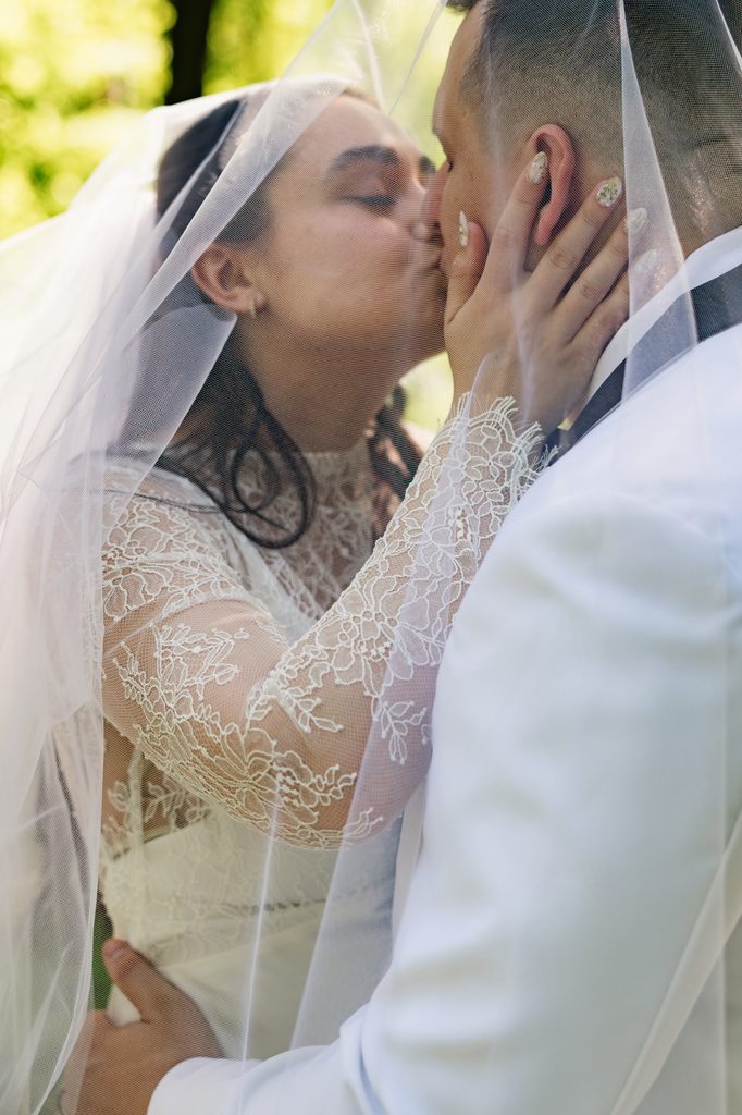 couples shares a kiss under the bride's veil during couples portraits in Northern VA wedding