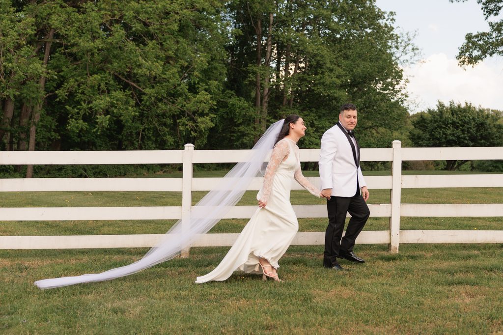 couple walks by a white picket fence after their Northern VA backyard wedding ceremony